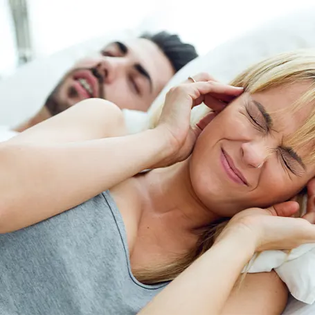 Een man die snurkt naast een vrouw die niet kan slapen