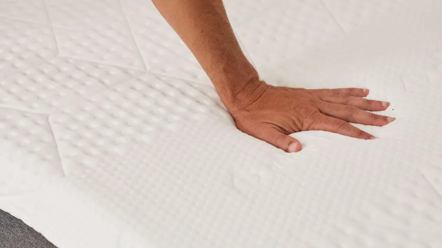 Een hand die de comforthoes van het Emma Original Plus matras aanraakt