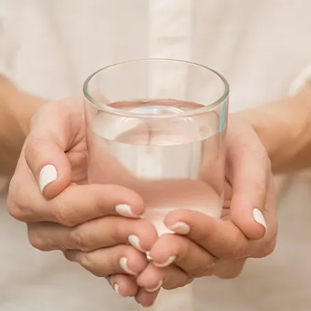 Een afbeelding van een vrouw die een glas water vasthoudt.