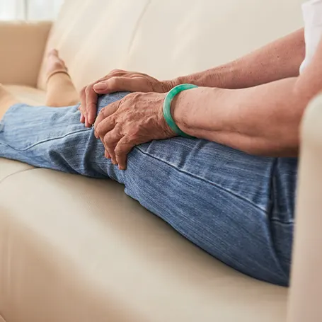 Een afbeelding van een oudere vrouw die haar knie aanraakt