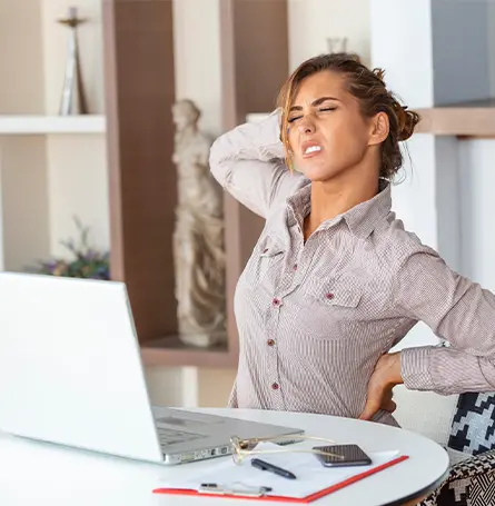 Een afbeelding van een vrouw zittend aan een bureau met een geblesseerde rug